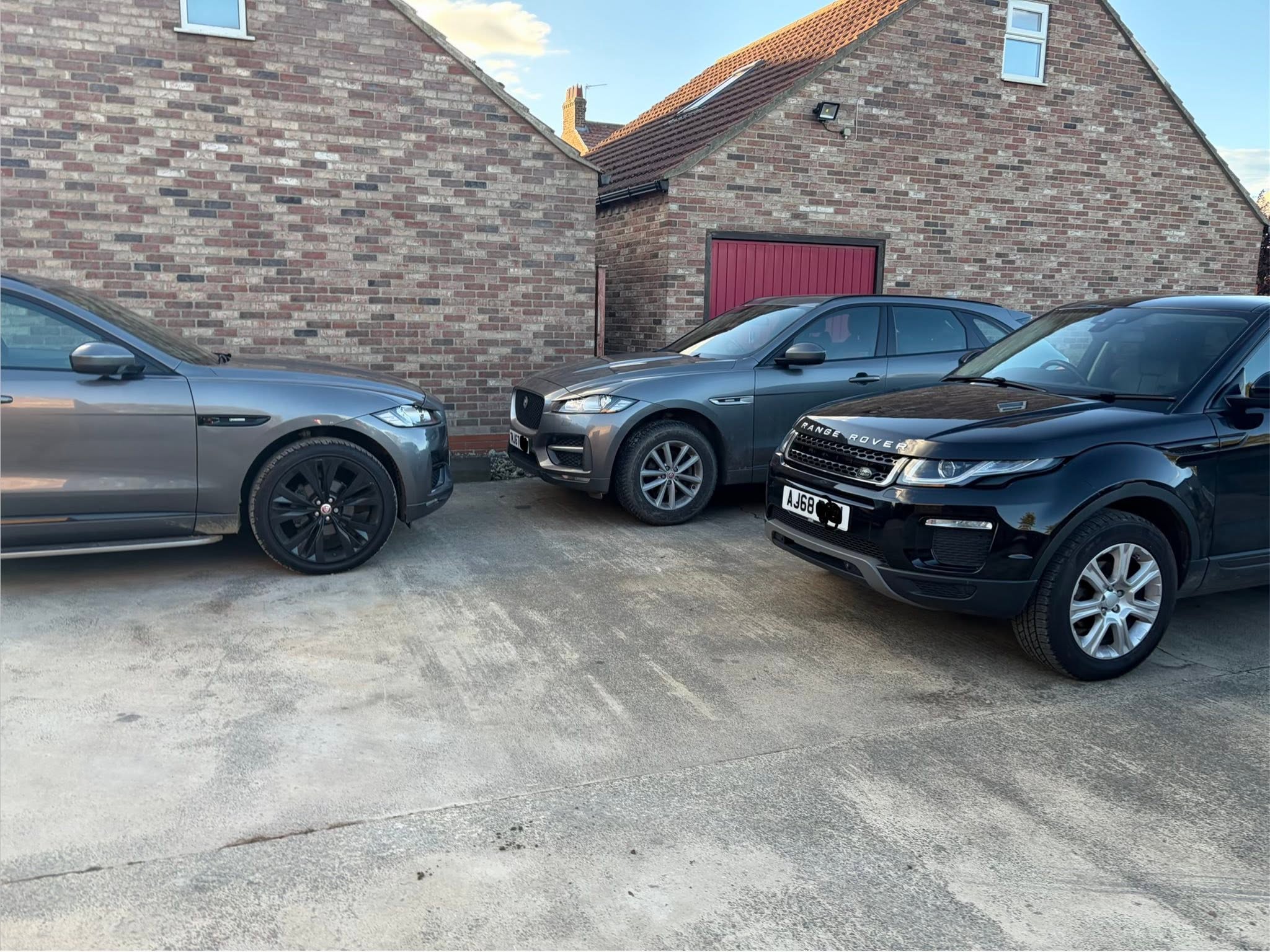 Customer SUVs parked in the yard beside the brick outbuildings
